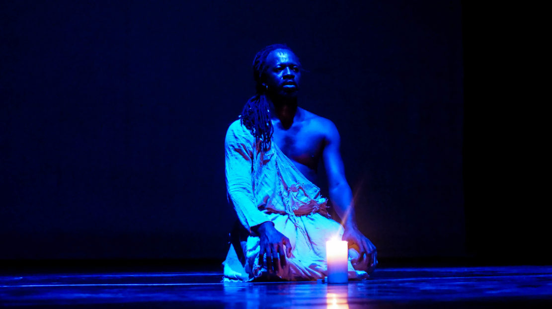 Aguibou Bougobali Sanou sitting on a stage in blue light.