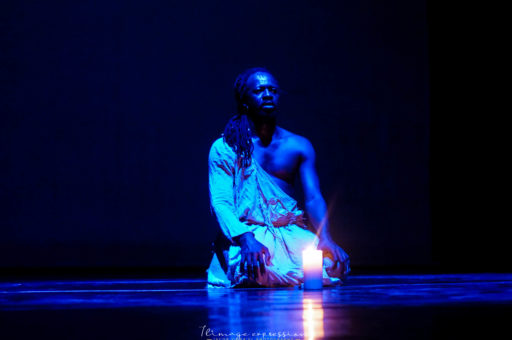 Aguibou Bougobali Sanou sitting on a stage in blue light.