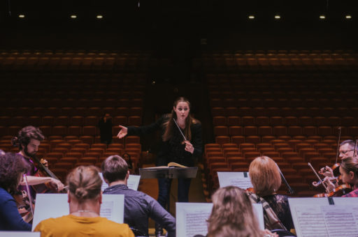 Woman conducting musicians in theater