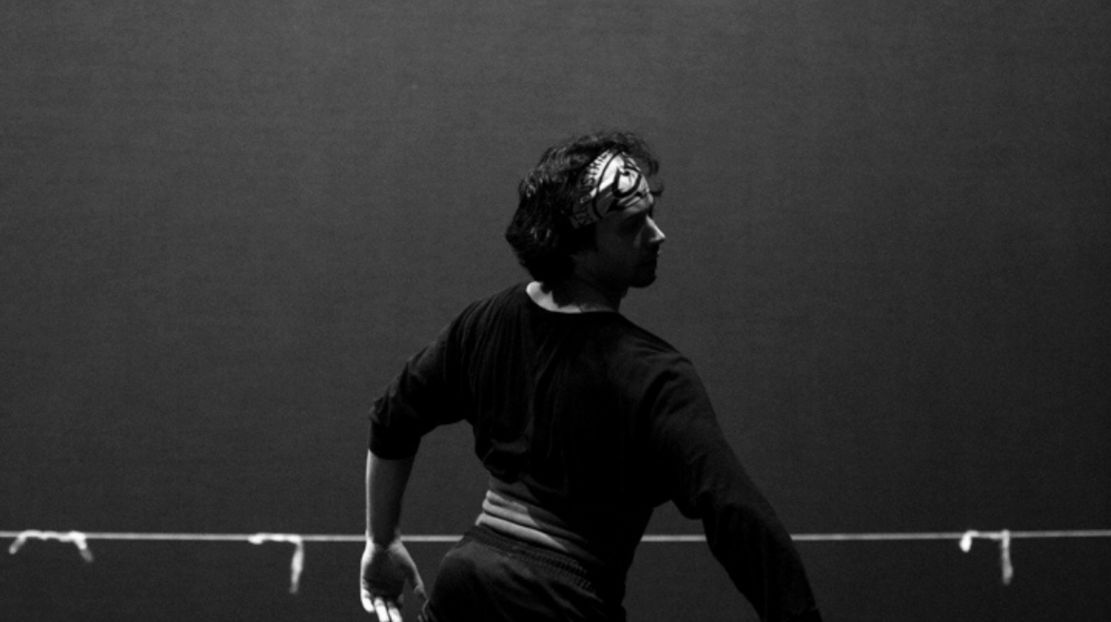 Herman Cornejo dancing on a stage in black and white.