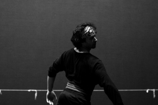 Herman Cornejo dancing on a stage in black and white.